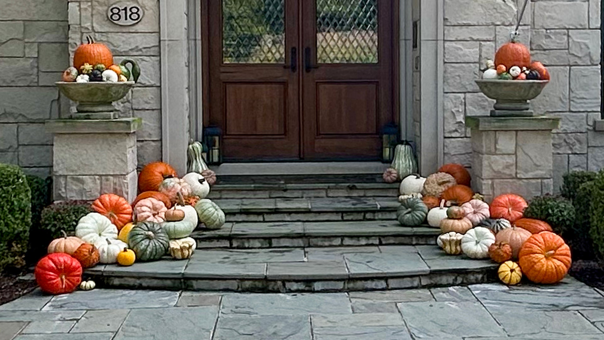 Decorative pumpkins and gourds on steps leading to a door with stone walls.