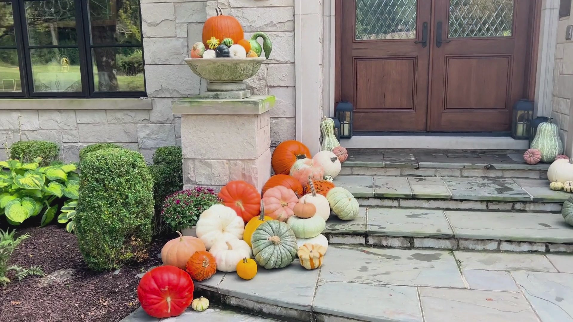 colorful pumpkins in front of a stone home with pumpkins in a large urn